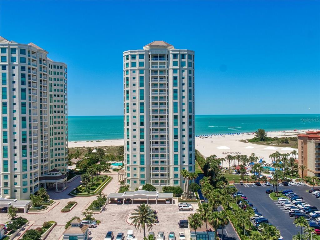 An aerial view of a tall residential building located on a sandy beach — 1170 GULF BOULEVARD UNIT 404, CLEARWATER BEACH, FL