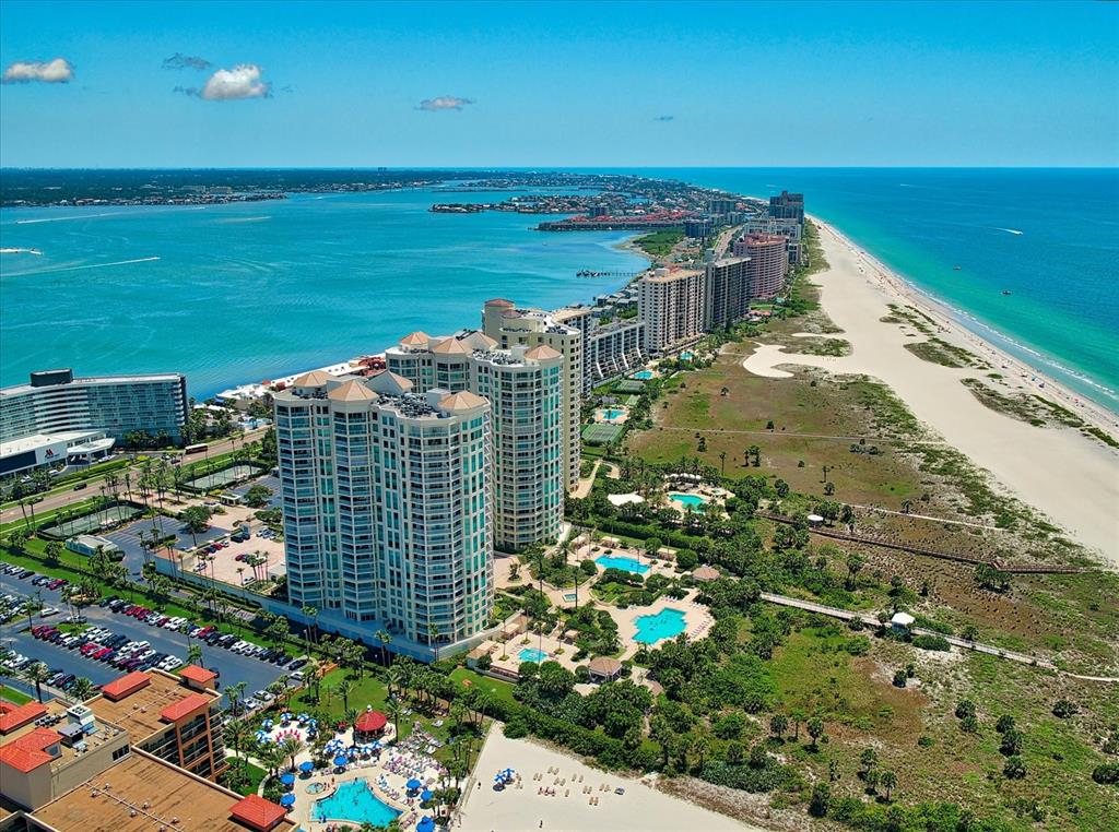 An aerial view of high-rise beachfront condominiums along a sandy coastline with swimming pools — 1170 GULF BOULEVARD UNIT 404, CLEARWATER BEACH, FL