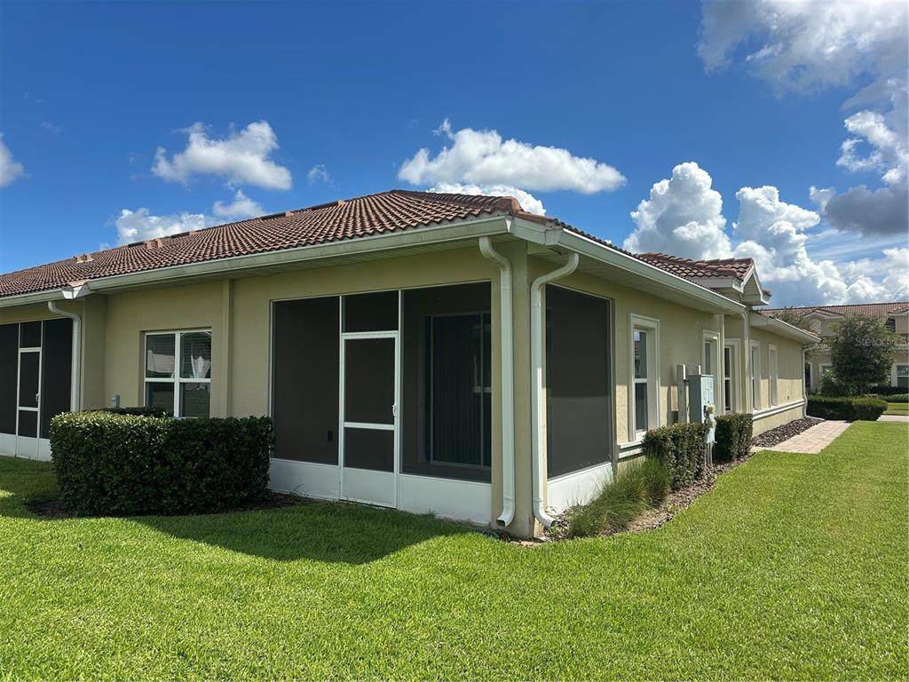 The exterior of a tan house features a screened-in patio and a tiled roof — 1068 QUAKER RIDGE LANE, DAVENPORT, FL