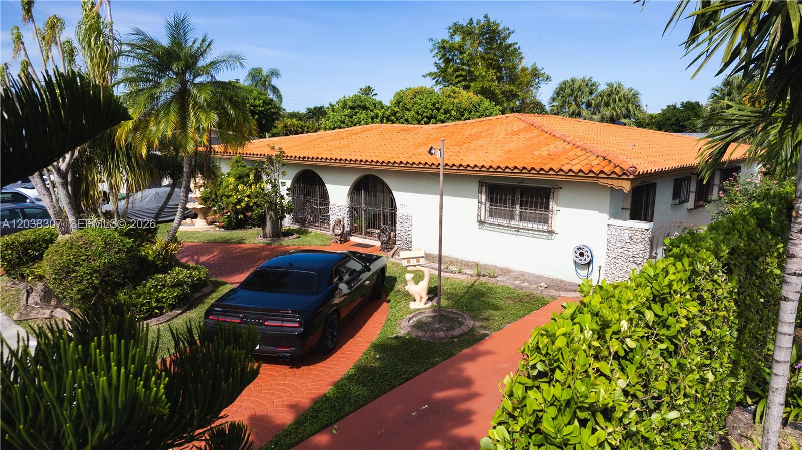 A single-story house with a terracotta tile roof and a paved driveway featuring a car — 9601 SW 66th St, Miami FL 33173, MIAMI, FL
