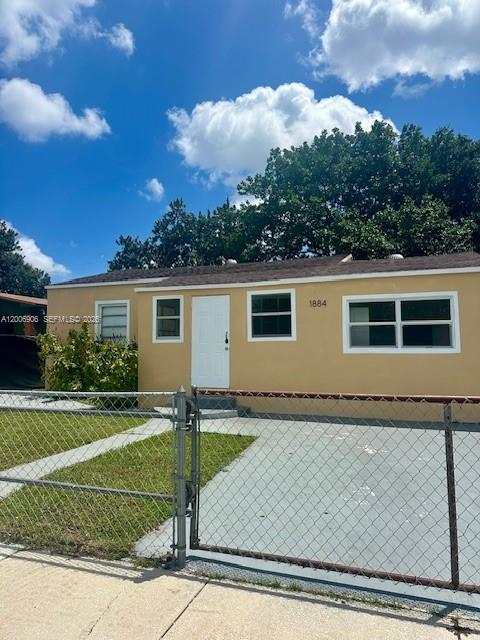 A single-story tan house with a white door and a chain-link fence in front — 1884 NW 52nd St # 0, Miami FL 33142, MIAMI, FL