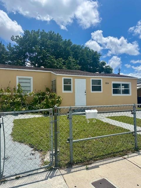 A single-story, light-yellow house with a white door and a chain-link fence in front — 1884 NW 52nd St # 0, Miami FL 33142, MIAMI, FL