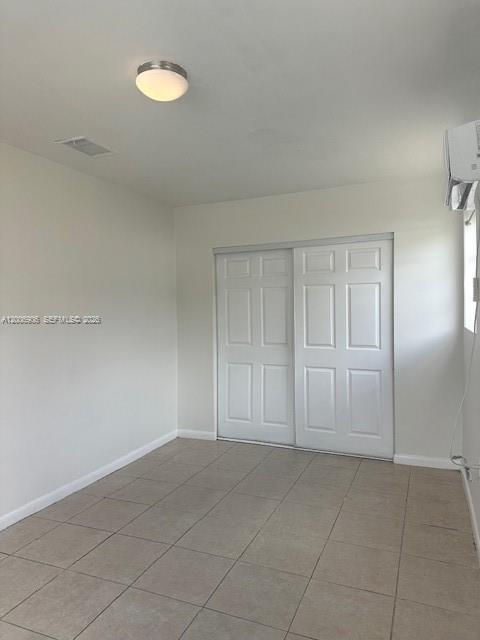 An empty room features white walls, tiled flooring, a ceiling light, and white closet doors — 1884 NW 52nd St # 0, Miami FL 33142, MIAMI, FL