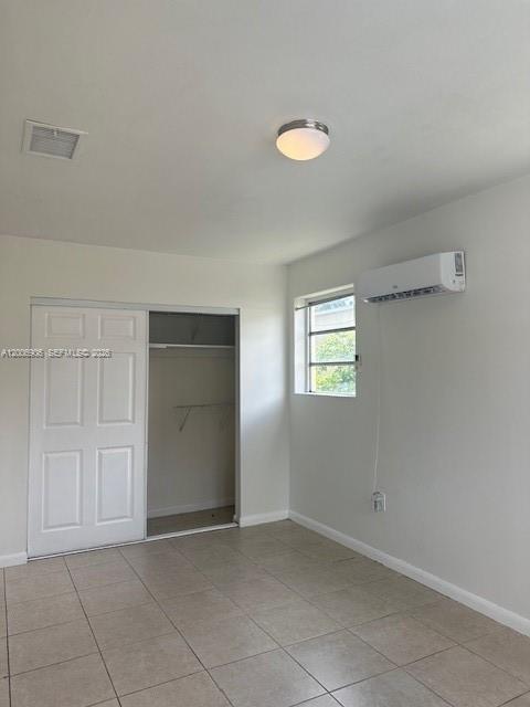 A bedroom features tile flooring, a sliding closet door, a window, and a wall-mounted air conditioner — 1884 NW 52nd St # 0, Miami FL 33142, MIAMI, FL