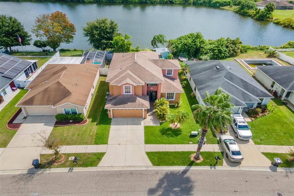 An aerial view shows a two-story house with a tan exterior situated between two neighbors — 11302 SOUTHWIND LAKE DRIVE, GIBSONTON, FL