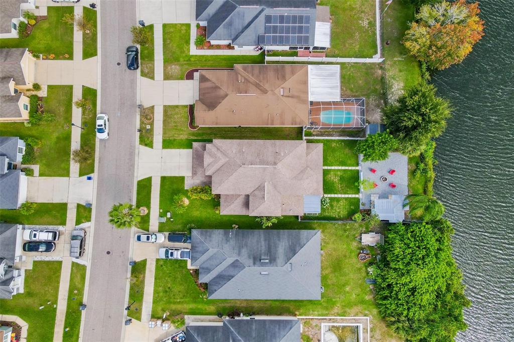 An aerial view shows several suburban houses with driveways, lawns, and a lakefront backyard — 11302 SOUTHWIND LAKE DRIVE, GIBSONTON, FL