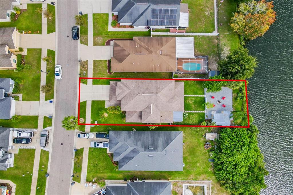 An aerial view shows a residential house with a backyard patio and fire pit area — 11302 SOUTHWIND LAKE DRIVE, GIBSONTON, FL