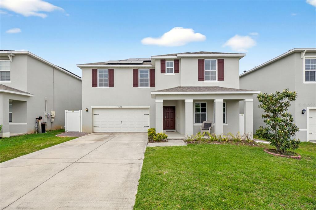 A two-story suburban house with a two-car garage, light gray siding, and maroon shutters — 9649 BLACK WALNUT DRIVE, CLERMONT, FL