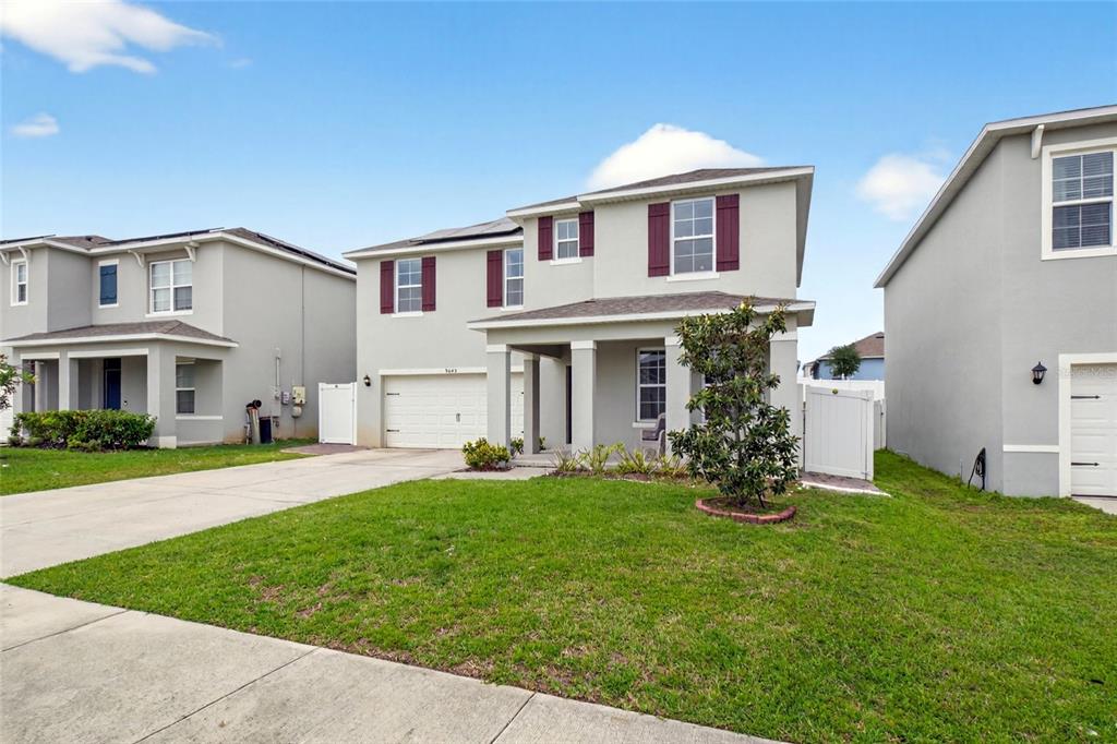 A two-story suburban house with a gray stucco exterior, white garage door, and front lawn — 9649 BLACK WALNUT DRIVE, CLERMONT, FL