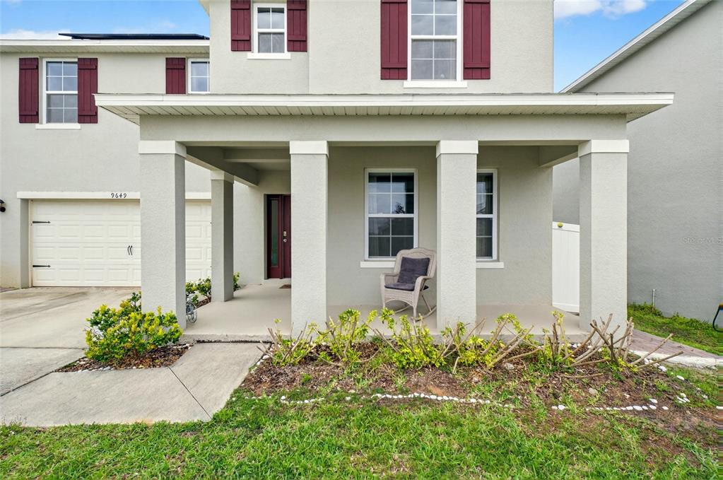 A two-story house with a covered front porch, a rocking chair, and a garage — 9649 BLACK WALNUT DRIVE, CLERMONT, FL
