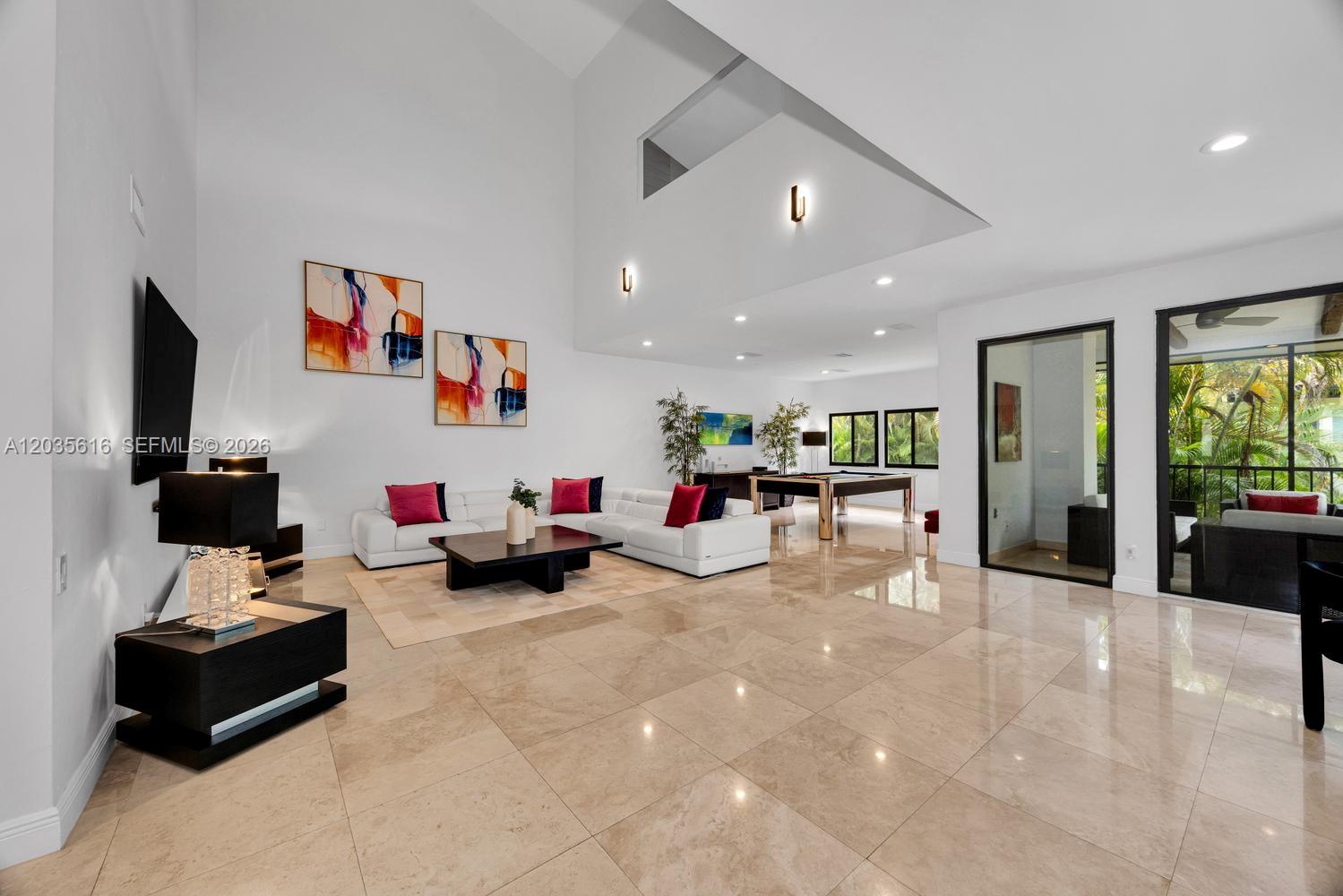 A spacious living room features high ceilings, white walls, tile flooring, and a pool table — 2000 S Bayshore Dr # 65, Miami FL 33133, MIAMI, FL