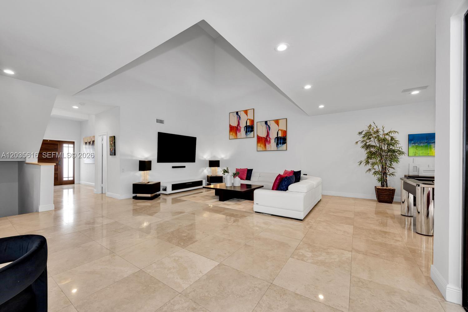 A spacious living room features white walls, high vaulted ceilings, and polished beige tile floors — 2000 S Bayshore Dr # 65, Miami FL 33133, MIAMI, FL