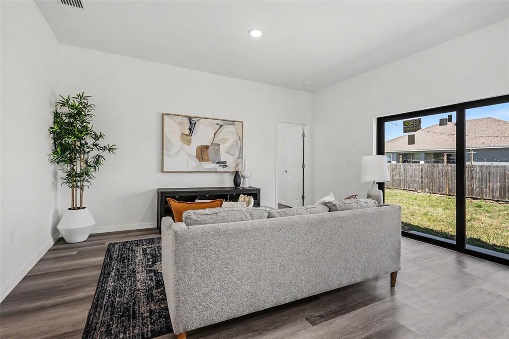 A living room features a gray sofa, a dark console table, and a sliding glass door — 1727 NE 12TH TERRACE, CAPE CORAL, FL
