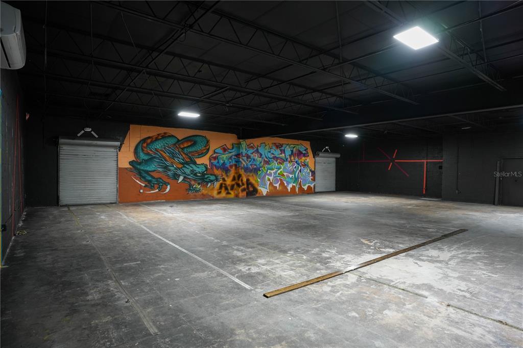 An industrial warehouse space features a concrete floor, black ceiling, and a large dragon mural — 4700 22ND AVENUE S UNIT 3, ST PETERSBURG, FL