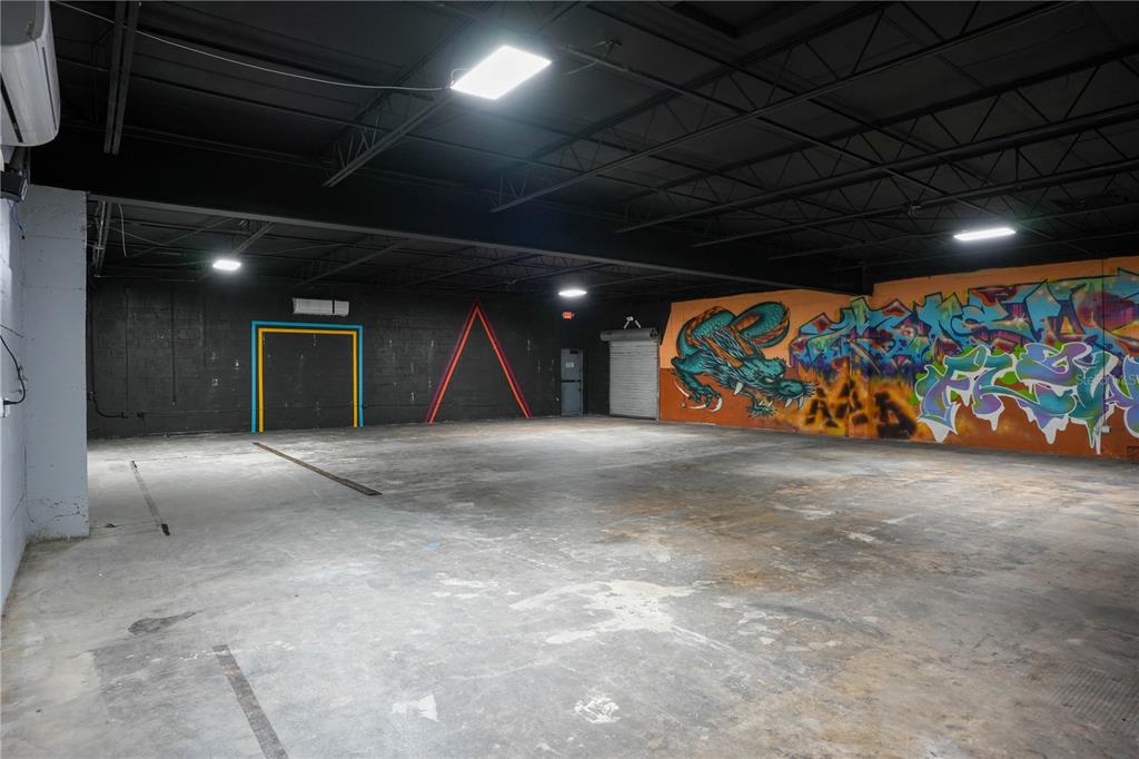 An industrial-style room features a concrete floor, black ceiling, and a wall with graffiti art — 4700 22ND AVENUE S UNIT 3, ST PETERSBURG, FL