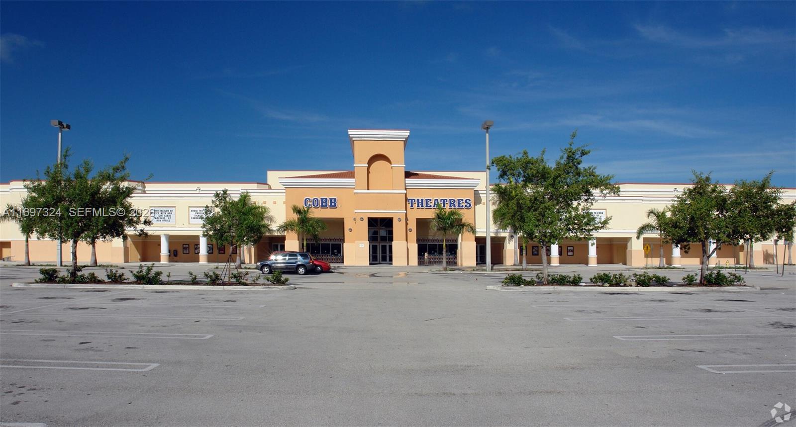 The exterior of a Cobb Theatres building features a tan facade and a large parking lot — 17355 NW 59th Ave, Hialeah FL 33015, HIALEAH, FL