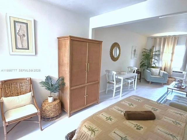 A bedroom features a wicker chair, a large wooden armoire, and a bed with linens — 1050 Pennsylvania Ave # 28, Miami Beach FL 33139, MIAMI BEACH, FL