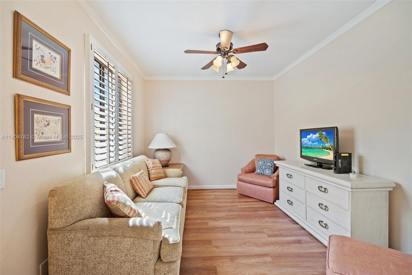 A living room features a beige sofa, a white dresser with a television, and wood-look flooring — 1634 Passion Vine Cir # 2, Weston FL 33326, WESTON, FL