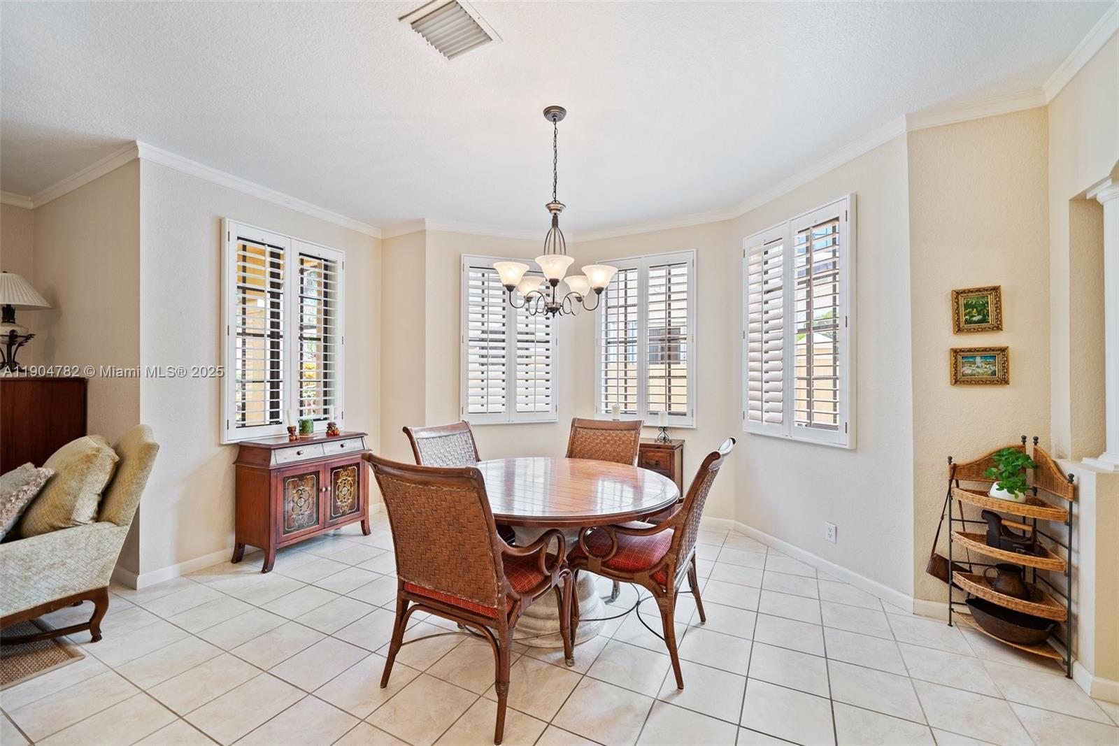 A dining area features a round wooden table, wicker chairs, tiled floors, and plantation shutters — 1634 Passion Vine Cir # 2, Weston FL 33326, WESTON, FL