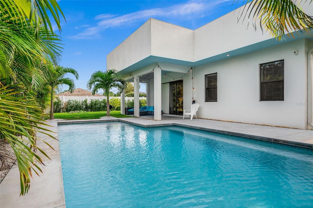 A modern house exterior features a backyard swimming pool and a covered patio area — 5351 MOELLER AVENUE, SARASOTA, FL