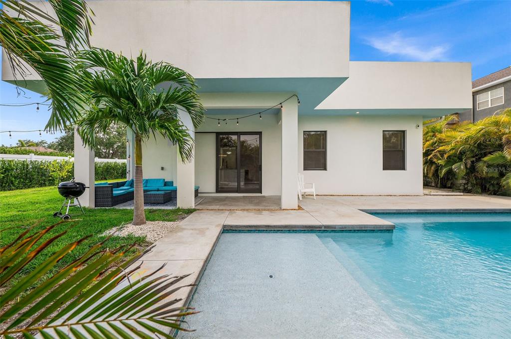 A modern white house exterior features a covered patio, a swimming pool, and palm trees — 5351 MOELLER AVENUE, SARASOTA, FL
