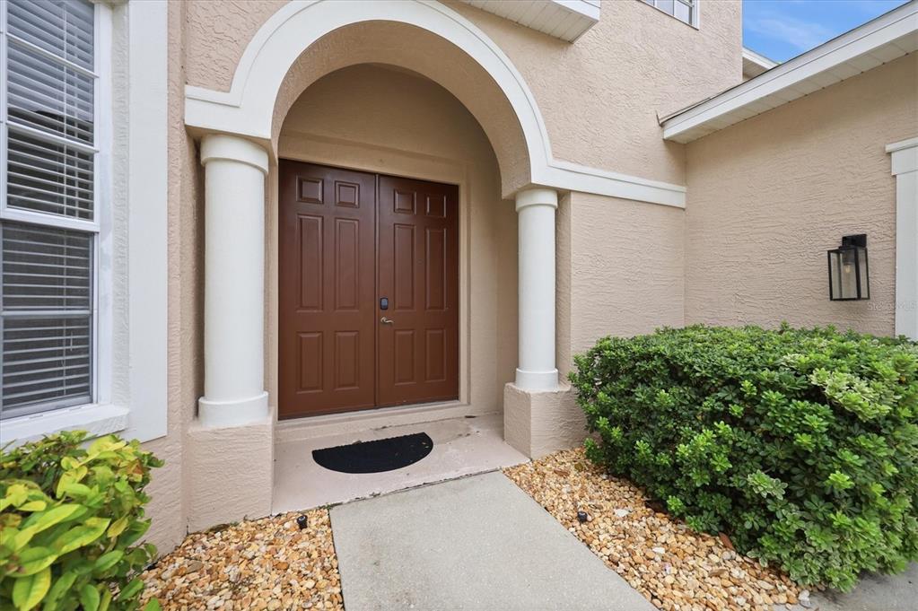 A tan stucco house exterior features a double front door under an arched entryway — 4907 50TH AVENUE W, BRADENTON, FL