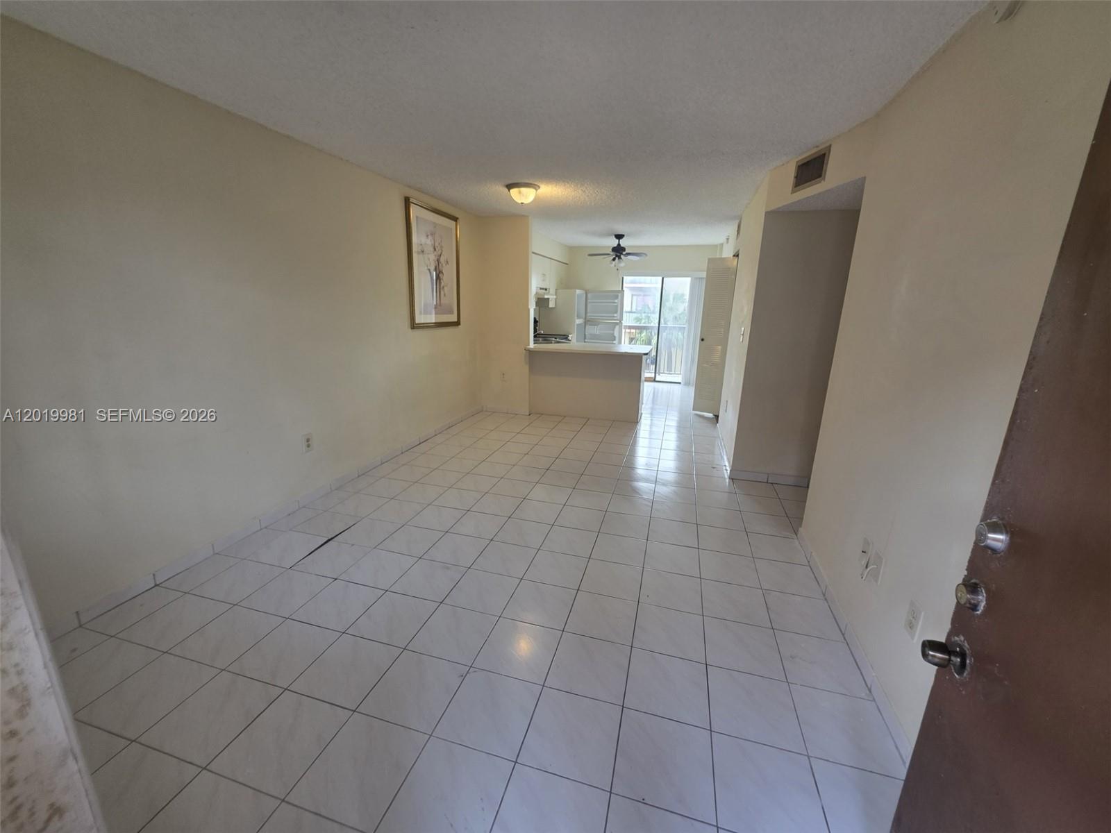 An interior view shows a tiled living area leading to a kitchen with a breakfast bar — 5500 W 21st Ct # 306, Hialeah FL 33016, HIALEAH, FL