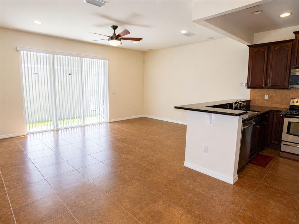 An open-concept kitchen and living area features tile flooring, dark wood cabinets, and sliding doors — 1515 BOWMORE DRIVE, CLEARWATER, FL