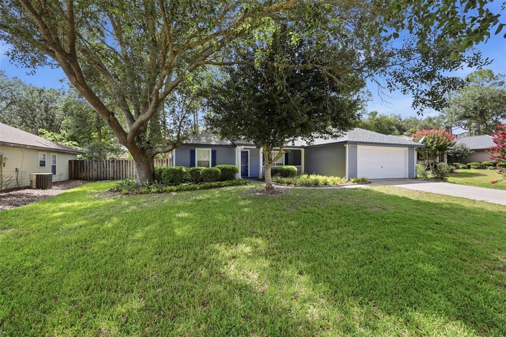 A single-story house with blue siding, a two-car garage, and a large front yard — 6828 SW 82ND TERRACE, GAINESVILLE, FL