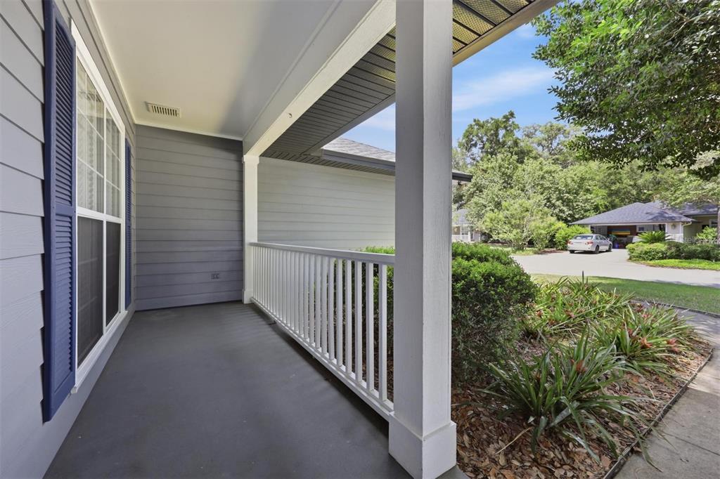 A covered porch features gray siding, a white railing, and a concrete floor — 6828 SW 82ND TERRACE, GAINESVILLE, FL