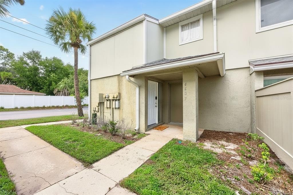 A two-story townhouse exterior features a covered entryway, a concrete walkway, and a palm tree — 4607 RING NECK ROAD UNIT 36C, ORLANDO, FL