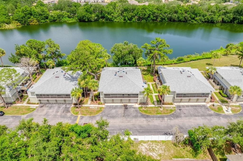 An aerial view shows three multi-unit residential buildings situated along a lakefront — 4607 RING NECK ROAD UNIT 36C, ORLANDO, FL