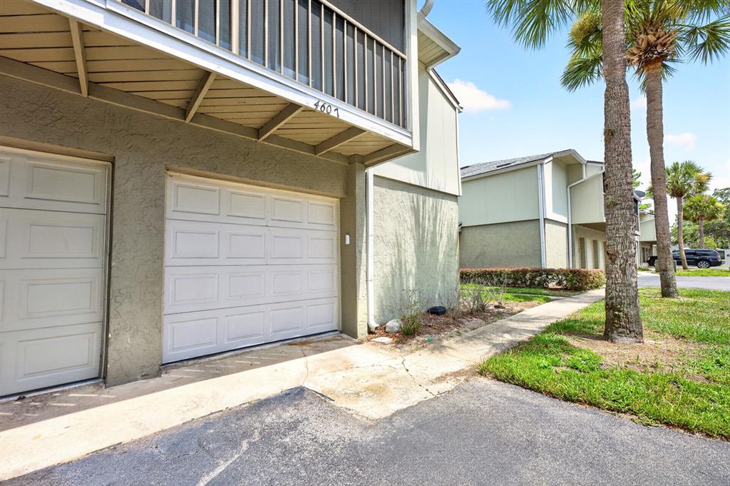 A white garage door is set into a tan building with a balcony above — 4607 RING NECK ROAD UNIT 36C, ORLANDO, FL