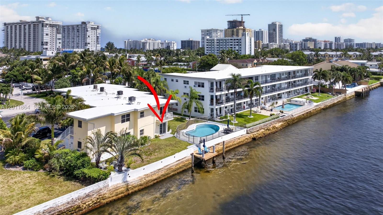 An aerial view shows a yellow two-story building with a balcony overlooking a waterfront pool — 615 S Riverside Dr # 5, Pompano Beach FL 33062, POMPANO BEACH, FL
