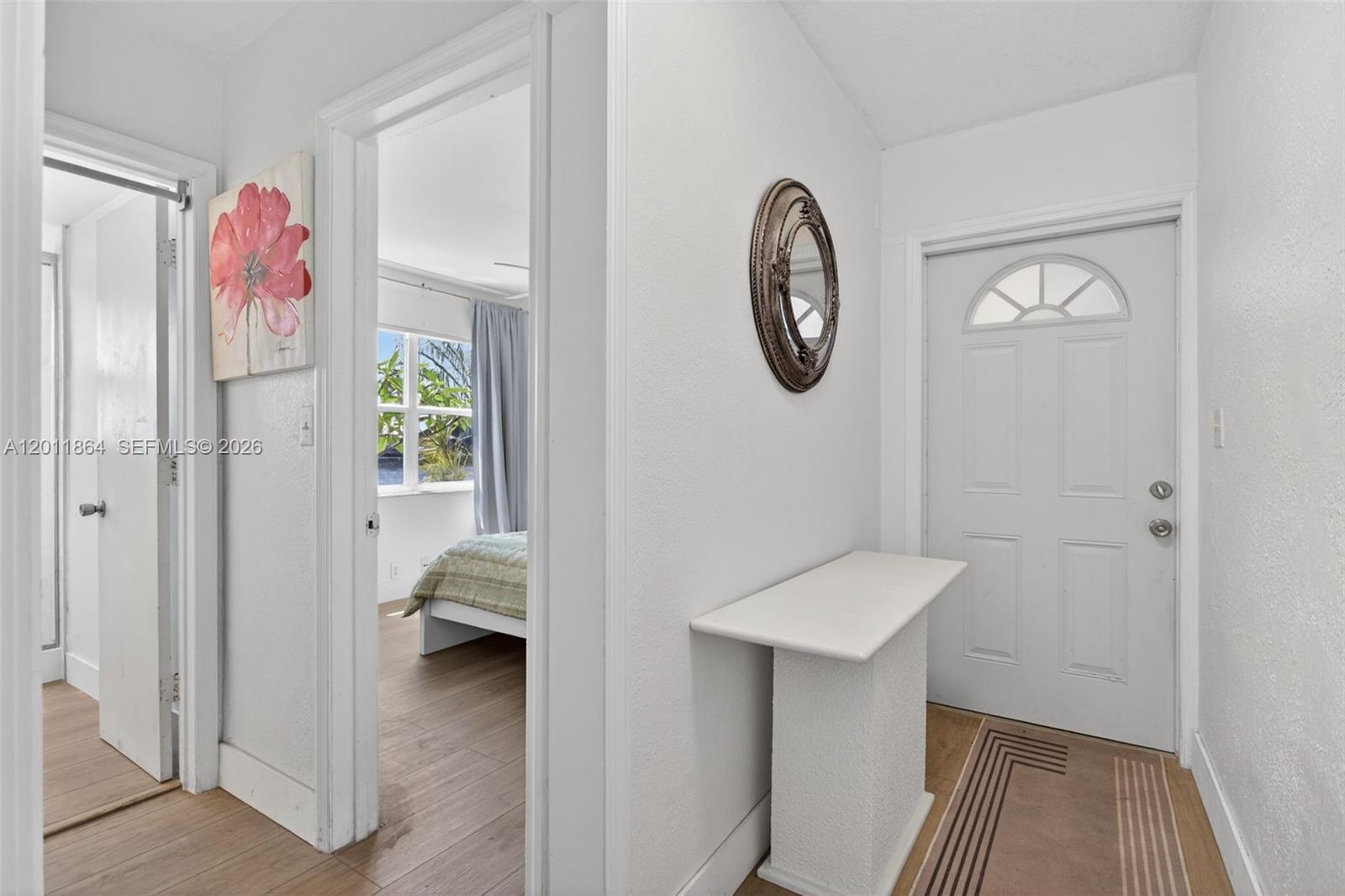 A white entryway features a small console table, a wall mirror, and a bedroom doorway — 615 S Riverside Dr # 5, Pompano Beach FL 33062, POMPANO BEACH, FL