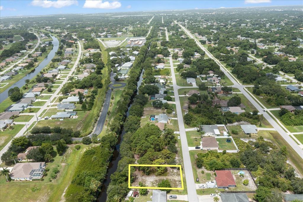 An aerial view shows a vacant, rectangular lot bordered by a canal and a road — 10485 GREENWAY AVENUE, ENGLEWOOD, FL
