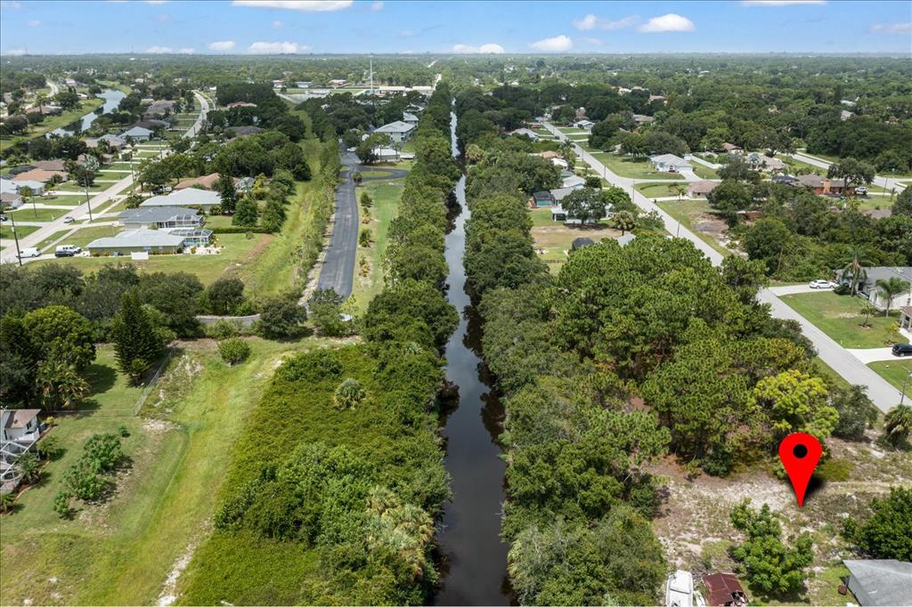 An aerial view shows a narrow canal running between residential lots and dense trees — 10485 GREENWAY AVENUE, ENGLEWOOD, FL