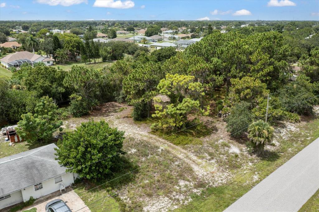 An aerial view shows a vacant, wooded lot situated between residential houses and a road — 10485 GREENWAY AVENUE, ENGLEWOOD, FL