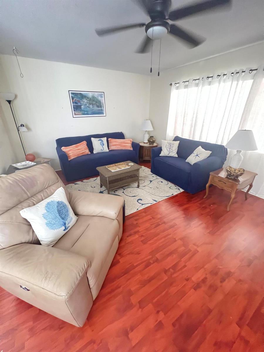 A living room features blue sofas, a tan recliner, and wood flooring under a ceiling fan — 165 Easthampton G, West Palm Beach FL 33417, WEST PALM BEACH, FL