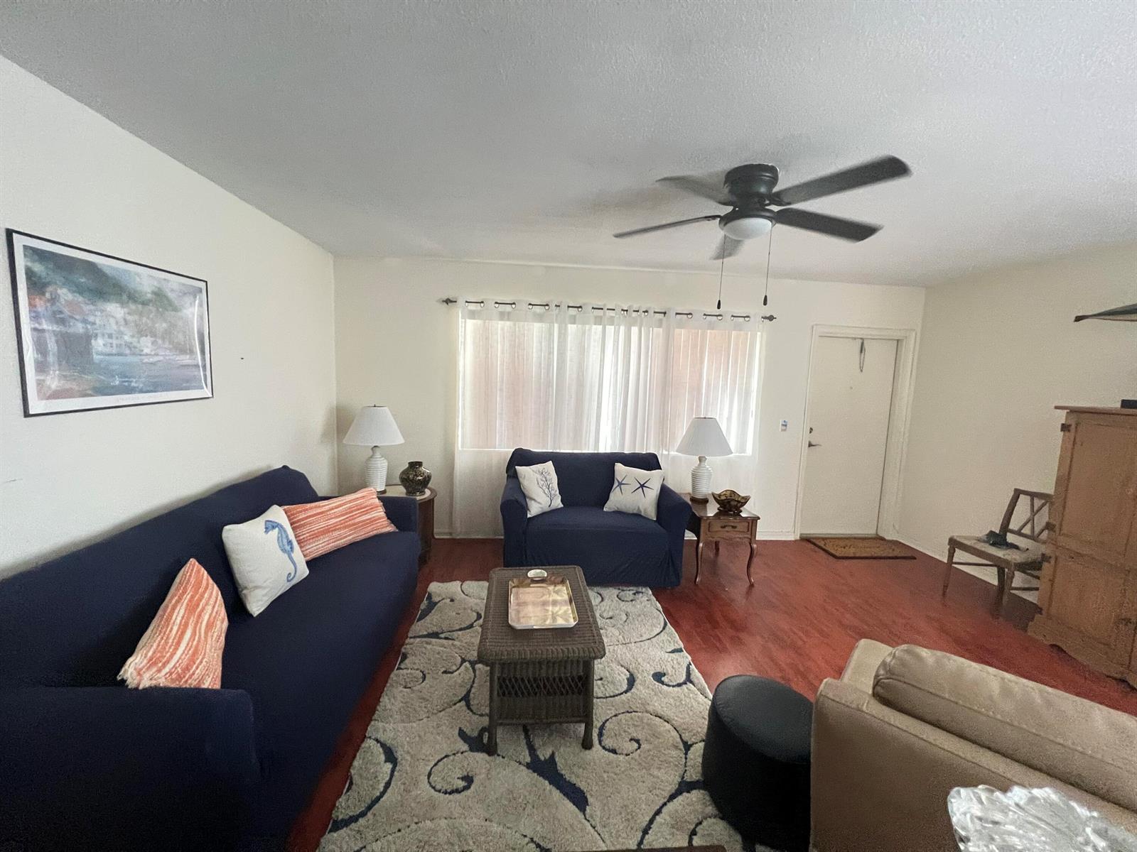 A living room features navy blue furniture, a patterned area rug, and wood-look flooring — 165 Easthampton G, West Palm Beach FL 33417, WEST PALM BEACH, FL