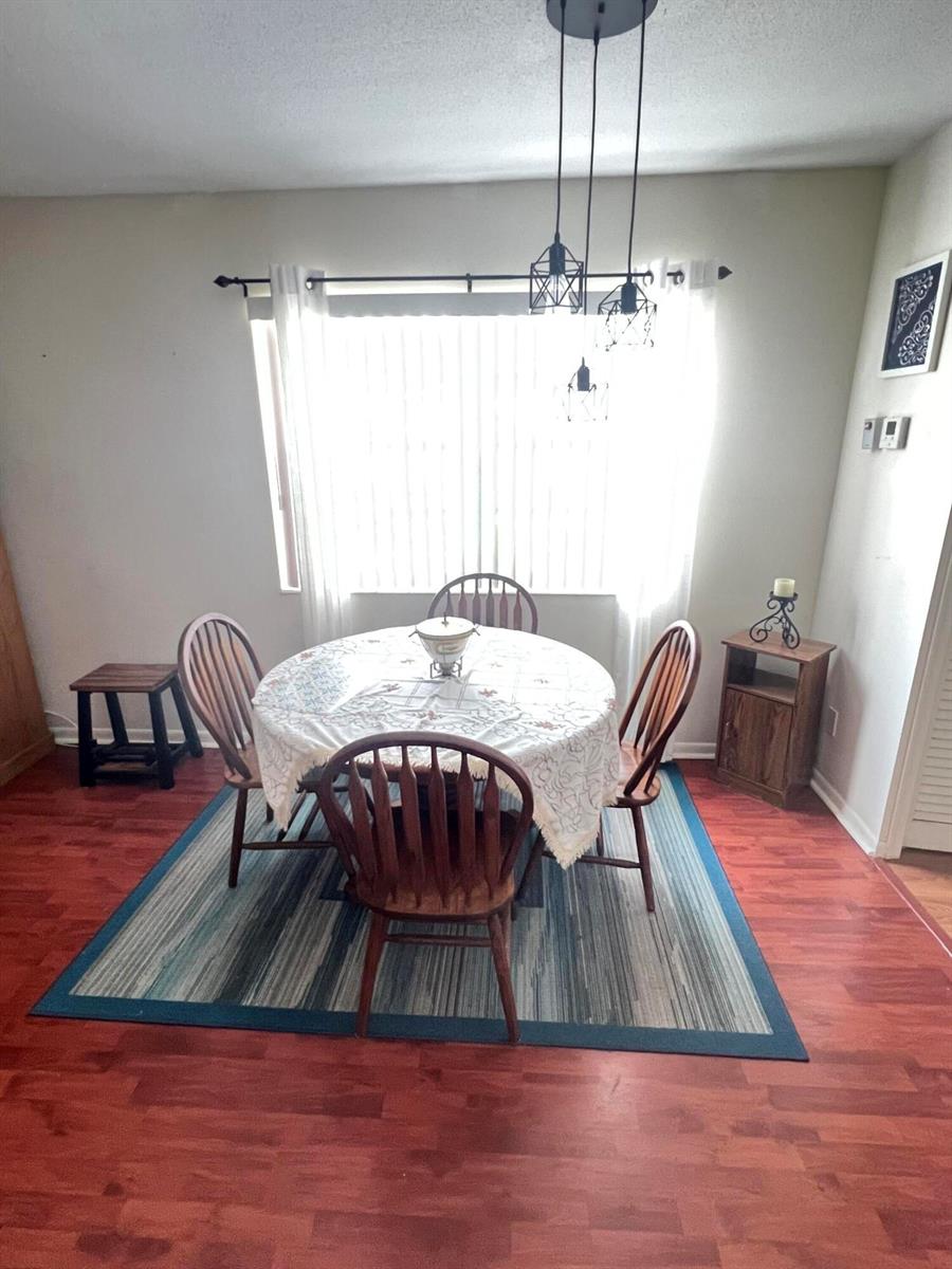 A dining area features a round table with four wooden chairs on a blue rug — 165 Easthampton G, West Palm Beach FL 33417, WEST PALM BEACH, FL