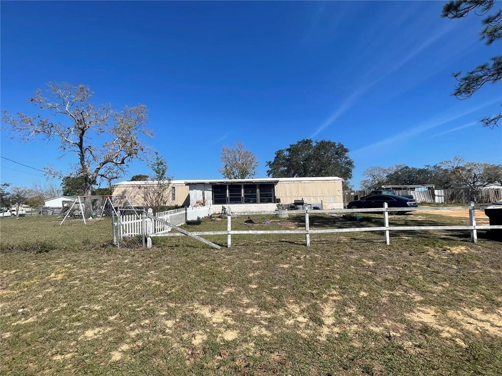 A single-story manufactured home sits on a grassy lot behind a white wooden fence — 4385 DIETZ ROAD, BARTOW, FL