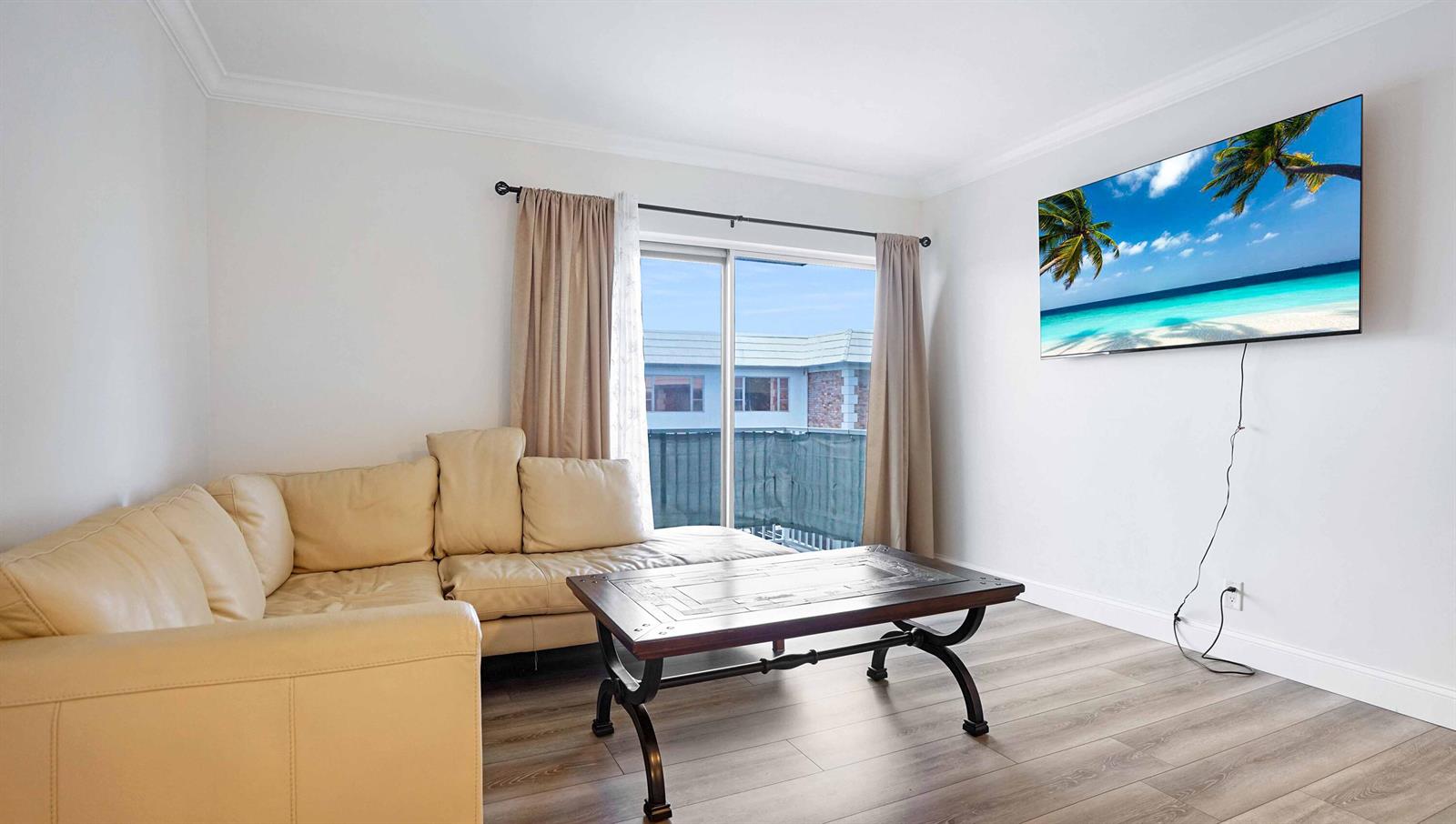 A living room features a beige sectional sofa, a coffee table, and a wall-mounted television — 330 S Cypress Road # 625, Pompano Beach FL 33060, POMPANO BEACH, FL
