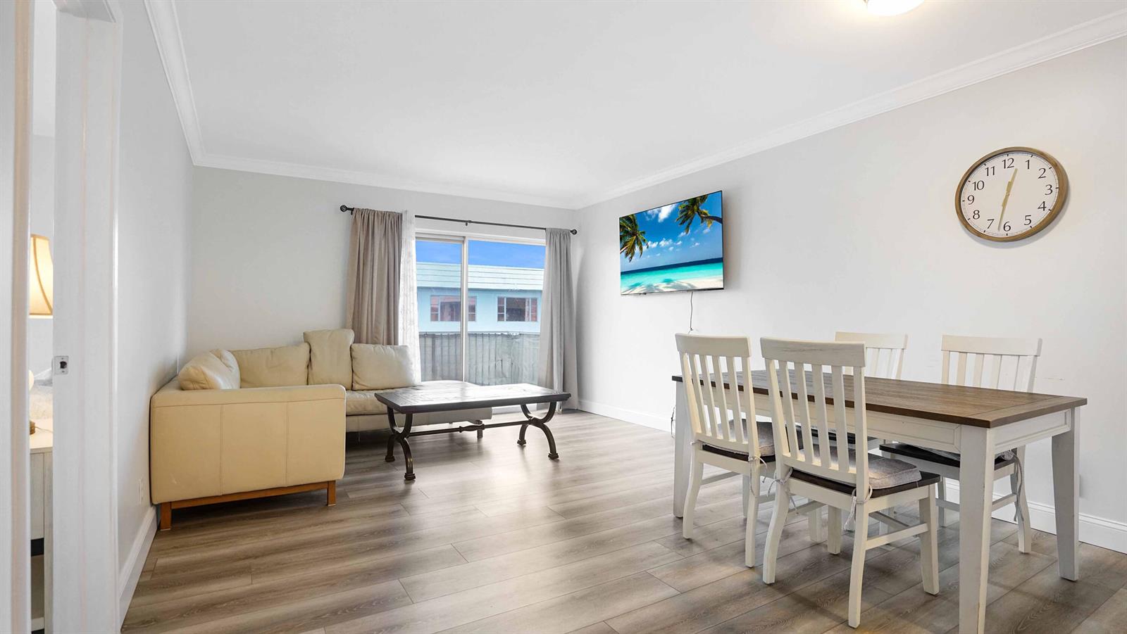 A living and dining area features light wood-look flooring, a beige sofa, and a wall-mounted television — 330 S Cypress Road # 625, Pompano Beach FL 33060, POMPANO BEACH, FL
