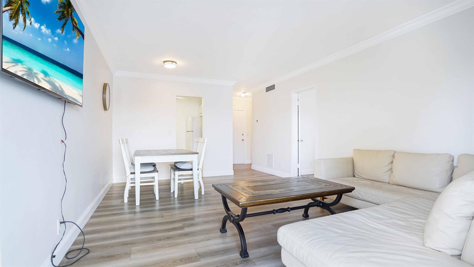 A living and dining area features light wood-look flooring, white walls, and a sectional sofa — 330 S Cypress Road # 625, Pompano Beach FL 33060, POMPANO BEACH, FL