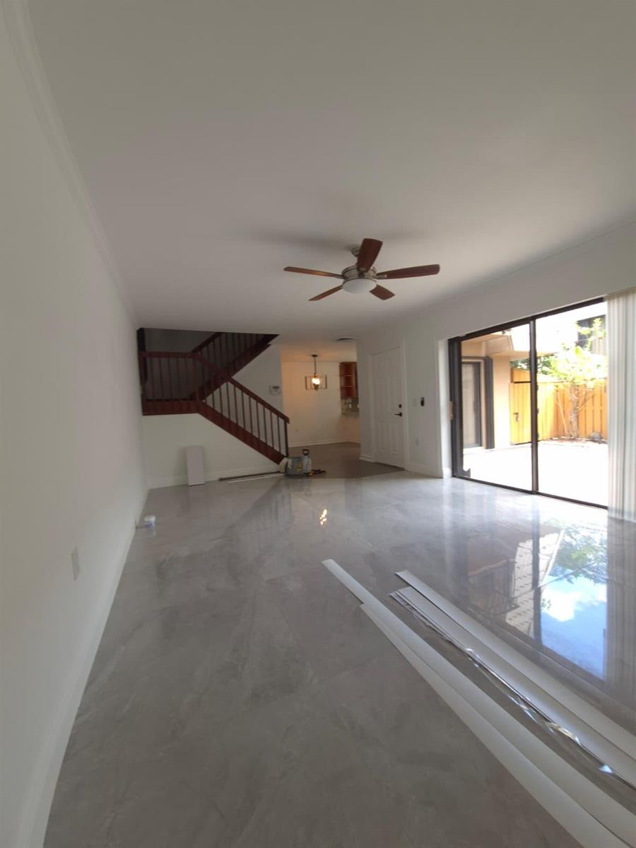 A living room with light gray tile floors, a ceiling fan, and a wooden staircase — 5012 50th Way, West Palm Beach FL 33409, WEST PALM BEACH, FL