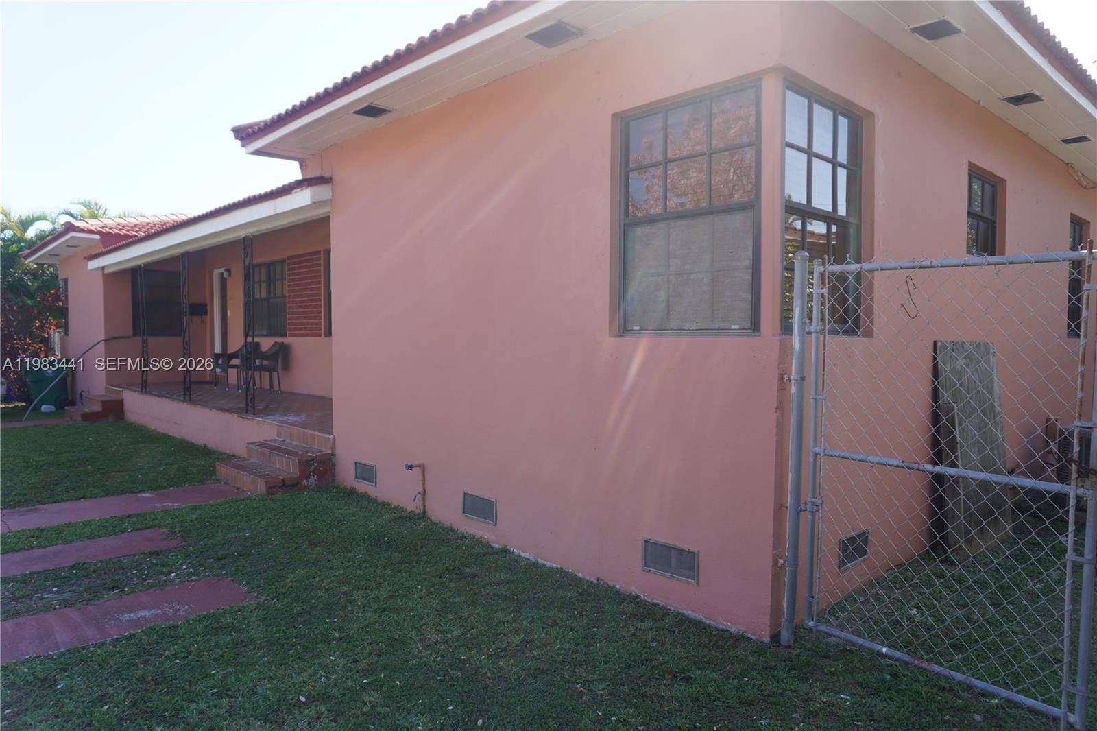 A side view of a pink house with a porch and a chain-link fence — 2660 SW 36th Ave, Miami FL 33133, MIAMI, FL