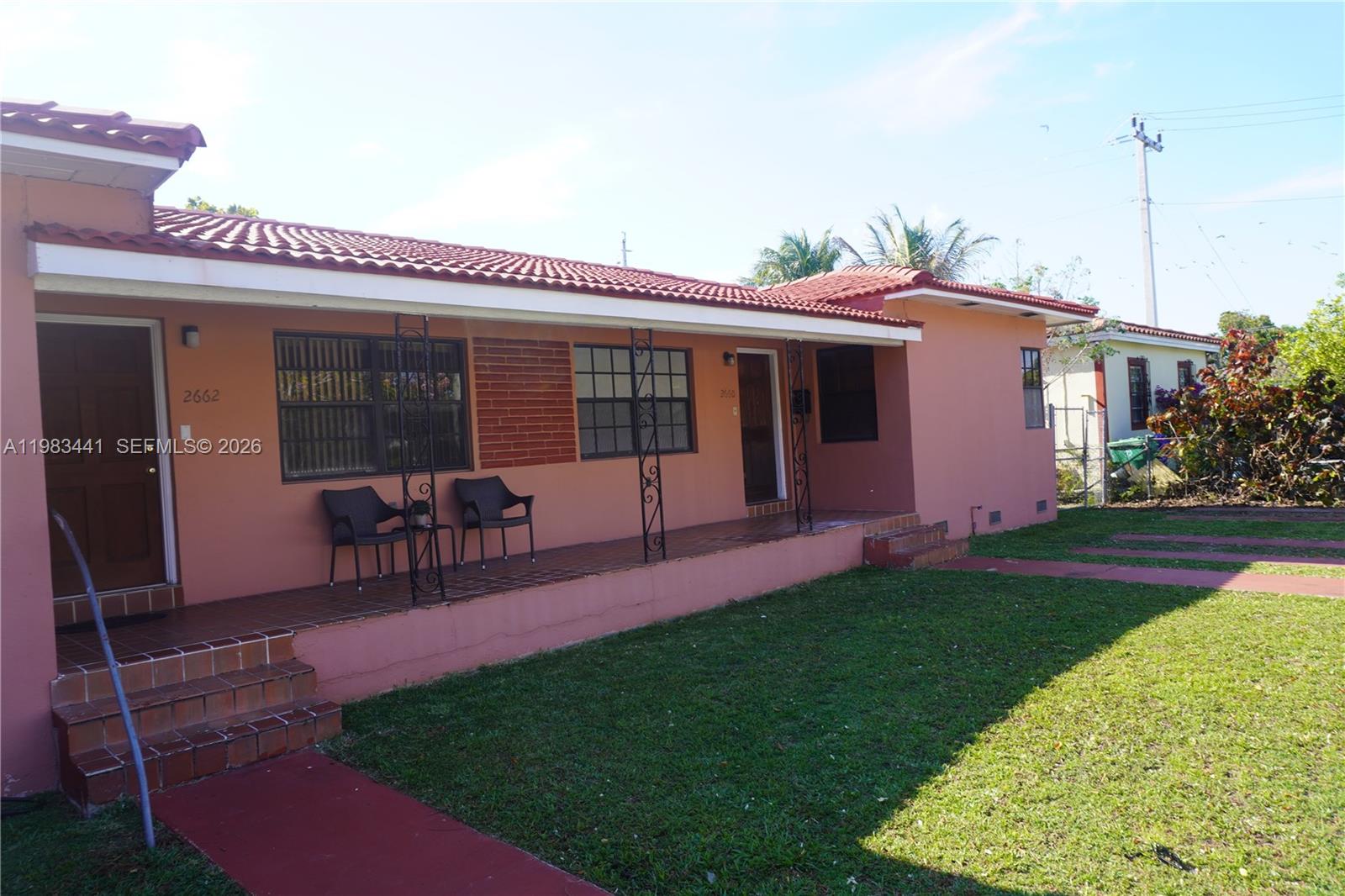 A peach-colored house with a tiled roof and a covered porch sits on a lawn — 2660 SW 36th Ave, Miami FL 33133, MIAMI, FL