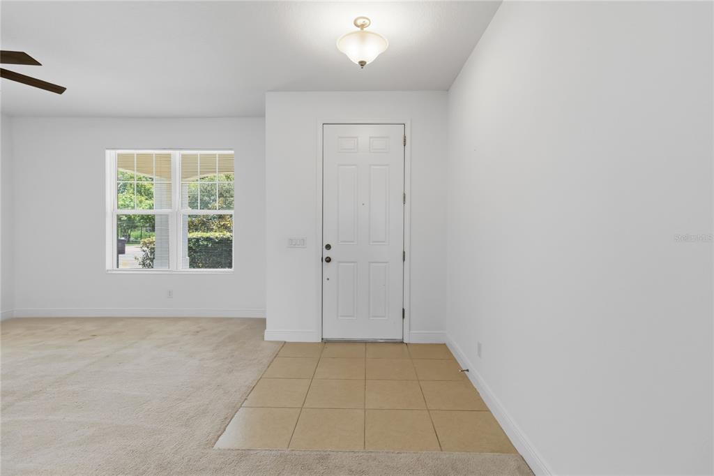 An entryway features a white front door, tiled flooring, and beige carpeting in an adjacent room — 3393 WAUSEON DRIVE, ST CLOUD, FL