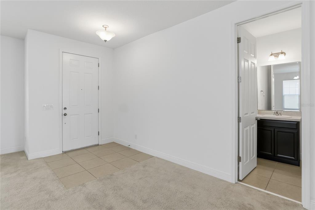 An entryway with tiled flooring and carpet leads to a bathroom with a dark vanity — 3393 WAUSEON DRIVE, ST CLOUD, FL